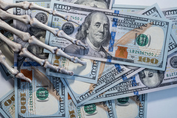 Skeleton hand holding banknotes of dollars.