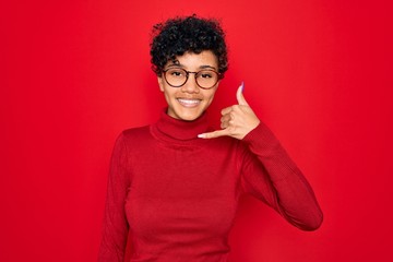 Young beautiful african american afro woman wearing turtleneck sweater and glasses smiling doing phone gesture with hand and fingers like talking on the telephone. Communicating concepts.