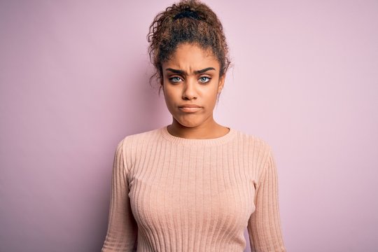 Young beautiful african american girl wearing casual sweater standing over pink background depressed and worry for distress, crying angry and afraid. Sad expression.