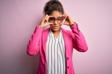 Beautiful african american businesswoman wearing jacket and glasses over pink background Trying to...