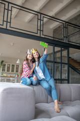 Obraz premium Mom and daughter wearing crowns and making selfie on a smartphone