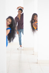 An young Indian Bengali group of friends/siblings in western outfit peeping out from a wall  on the balcony in white studio copy space background. Indian lifestyle.