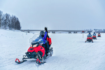 Fototapeta na wymiar People on snowmobile waving hand at frozen lake winter Rovaniemi