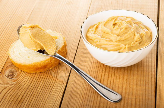 Spoon With Paste On Bread, Peanut Butter In Bowl On Wooden Table