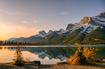 Sunrise on Mount Rundle with blue sky reflection on Rundle Forebay reservoir in autumn at Canmore