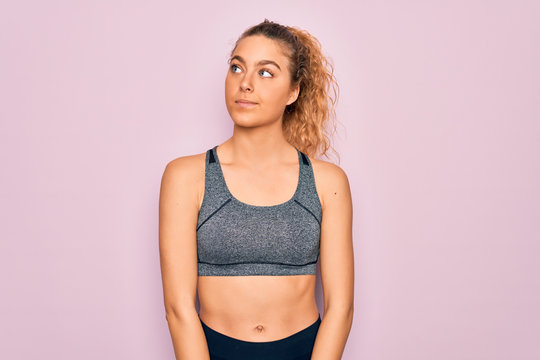 Young beautiful blonde sportswoman with blue eyes doing exercise wearing sportswear smiling looking to the side and staring away thinking.