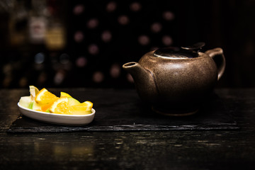 Mulled wine, sangria, mulled wine in a white Cup on a dark background, bar counter with fruit, tea and spices. Cinnamon sticks and orange