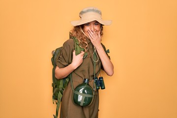 Young blonde explorer woman with blue eyes hiking wearing backpack and water canteen laughing and...