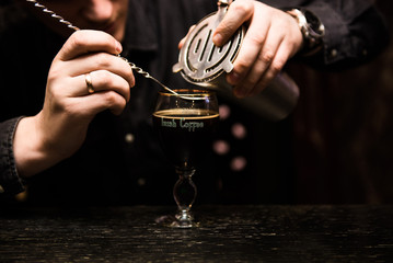 Irish Coffee cups with cream on a dark background, on the bar, warming cocktail, cooking process