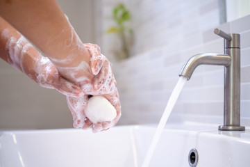 Women wash their hands with soap on the bathroom sinks. Frequent washing can help protect against...