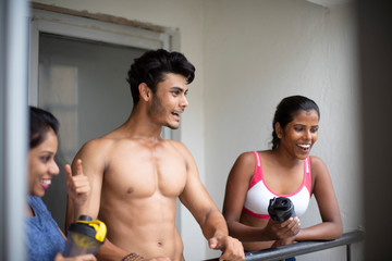 An young Indian Bengali group of friends/siblings are enjoying themselves standing on the balcony after work out in white background. Indian lifestyle.