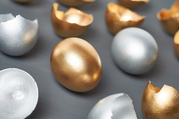 Scattered gold and silver eggs, shells on dark concrete background. Concept of easter, pricelless ideas, successful business investment or luxury breakfast