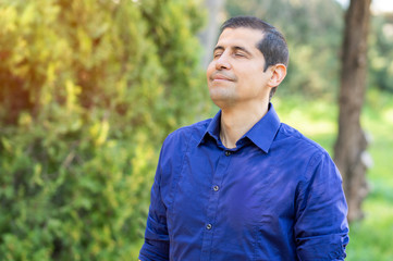 Relaxed adult man breathing fresh air in a forest