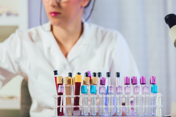 Lab technician assistant analyzing a blood sample in test tube at laboratory. Medical, pharmaceutical and scientific research and development concept.