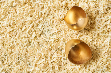 Fototapeta na wymiar Golden egg shells in nest. Concept of easter, pricelless ideas, successful business investment or luxury breakfast. Copy space. Top view