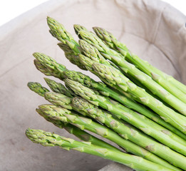 Bunches of asparagus tied on a burlap background.