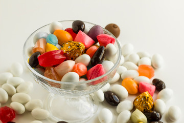 Almond candies covered in chocolate and colorful traditional Turkish candies in the glass candy bowl with leg.The Sugar Feast end of Ramadan.