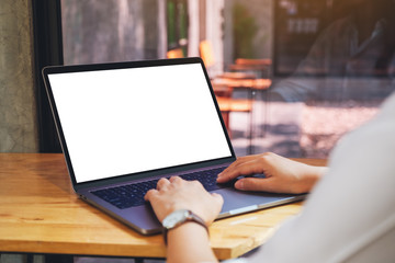 Mockup image of a woman using and typing on laptop computer with blank white desktop screen on...