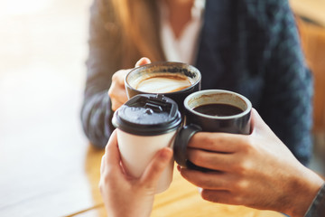 Closeup image of people enjoyed drinking and clinking coffee cups on the table in cafe