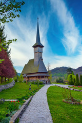 Fototapeta na wymiar Footpath to traditional Maramures neo gothic wooden church in Barsana monastery, Romania