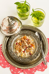 Traditional Turkish Dessert Noah Pudding,Asure in the vintage metal set on the white surface with fresh cold drink.