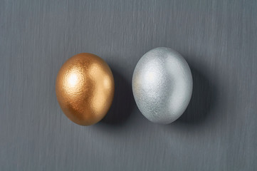 Golden and silver eggs on dark concrete background. Concept of easter, pricelless ideas, successful business investment or luxury breakfast. Top view