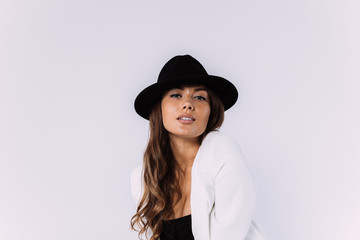 A laughing and smiling auburn haired woman in a white dress and black hat. Sittion on the wooden pallet. Isolated white background.