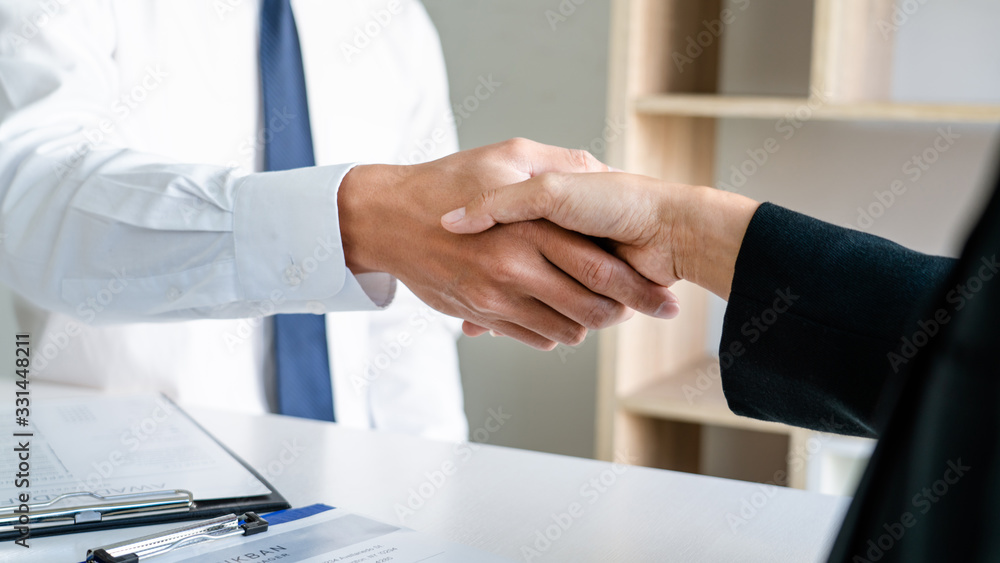 Wall mural businessman and businesswoman handshaking over the office desk after greeting new colleague, busines