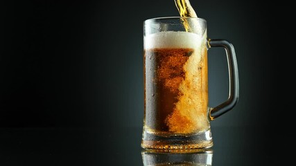 Super Slow Motion Shot of Pouring Fresh Beer into Glass on Black Background at 1000fps.