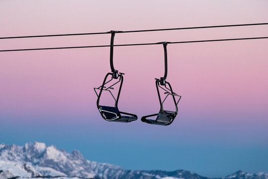 Stehender Sessellift mit rosamen Morgenrot zum Sonnenaufgang in den Alpen. 