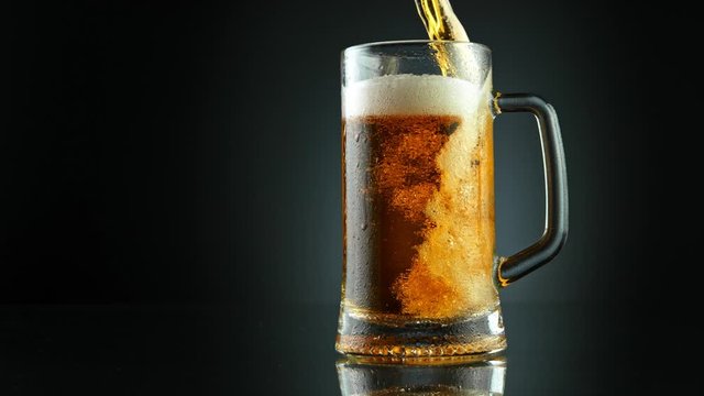 Super Slow Motion Shot of Pouring Fresh Beer into Glass on Black Background at 1000fps.