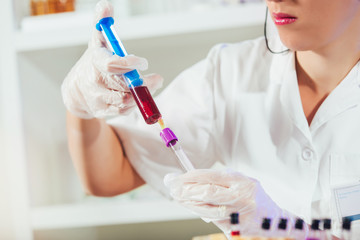 Lab technician assistant analyzing a blood sample at laboratory. Medical, pharmaceutical and scientific research and development concept.