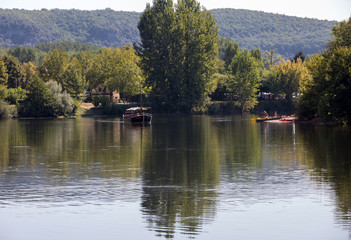  Canoeing and tourist boat, in French called gabare, on the river Dordogne at La Roque-Gageac, Aquitaine, France
