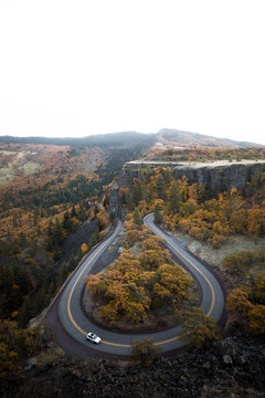 Wei&szlig;es Auto auf Passstra&szlig;e aus der Luft umrundet von Herbstlandschaft und bunten B&auml;umen. 