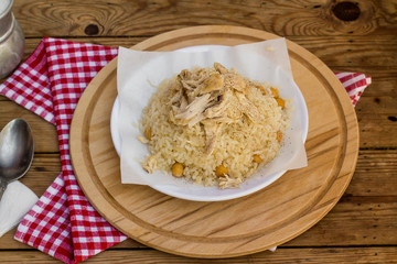 Traditional Turkish rice,cooked with chickpea and chicken meat on wooden table with napkin.street pilaf