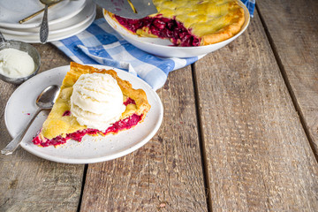 Homemade sweet sour cherry pie with vanilla ice cream, rustic wooden background copy space