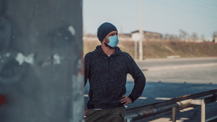 Hipster Man In A Medical Mask For Protection Against Flu Virus Or Coronavirus Outdoor Againts Highway. Corona Virus Pandemic. Epidemic Viral Respiratory Syndrome. 2019-nCoV. High Quality Photo