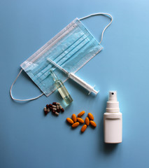 Medical mask with ampoule, syringe, antiseptic, medicines on a blue background. Covid19, coronavirus and epidemic content. Virus prevention and creating a vaccine against coronavirus. Copy space