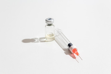 Close-up glass ampoule with medicine and single-use syringe ready for use. Light sterile background. Medicine concept.