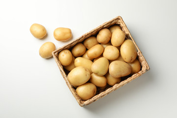 Basket with young potato on white background, top view