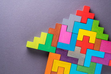Arrow of multi-colored wooden shapes on gray background.