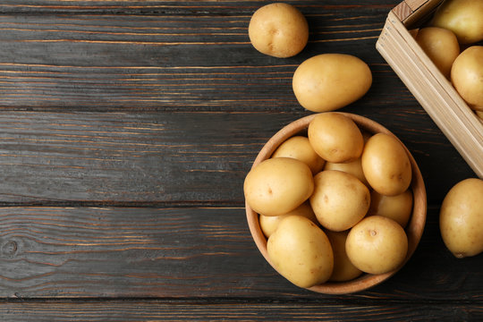 Bowl and basket with young potato on wooden background, top view