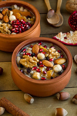 Traditional Turkish Dessert Asure,Ashura or Noah's Pudding in ceramic casserole bowls on wooden...