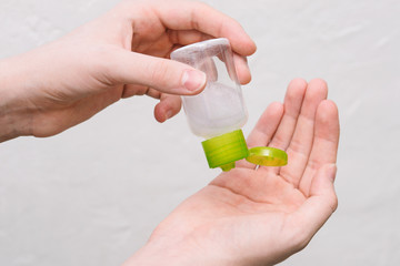 Hand antiseptic. Girl squeezing sand sanitizer on hands from a bottle. Small antibacterial hand sanitizer.