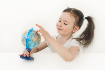 A child examines the globe. Cute girl exploring the planet earth. A child with two ponytails plays with a small globe