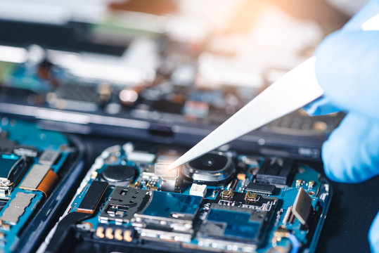 The asian technician repairing the smartphone's motherboard in the lab with copy space. the concept of computer hardware, mobile phone, electronic, repairing, upgrade and technology.