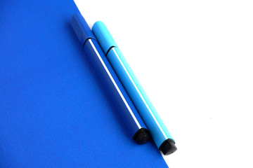 Two markers-blue shades on a blue and white background. School supplies. Suitable for advertising...
