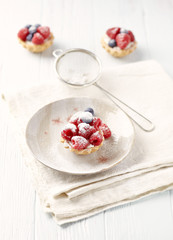  Little mascarpone tart with fresh raspberries on wooden background.