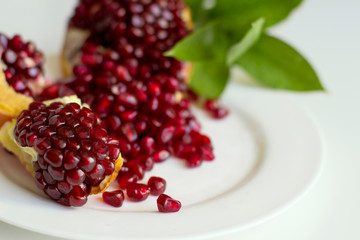  Juicy opened pomegranate with leaves on a white background. Eco healthy food. Grains of natural pomegranate.