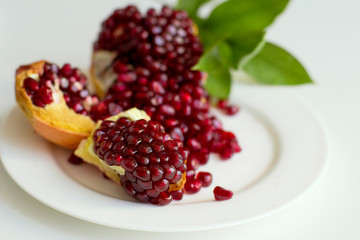 Juicy opened pomegranate with leaves on a white background. Eco healthy food. Grains of natural pomegranate.